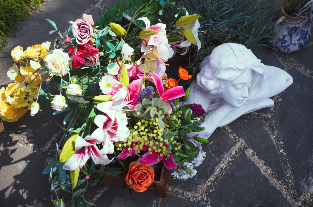 Composition florale colorée à côté d'une statue d'ange en marbre blanc.